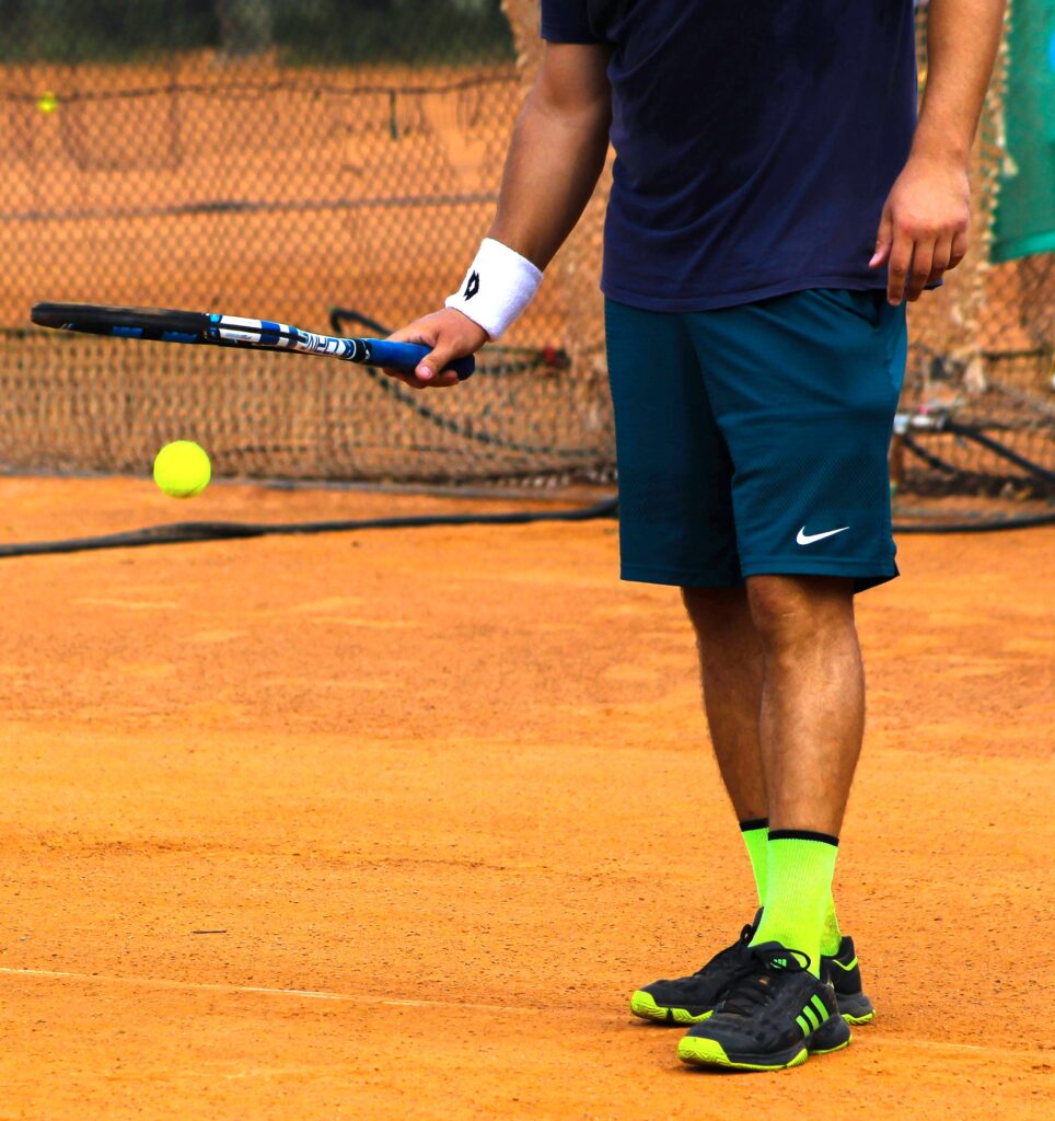Tennis Player Dribbling Ball with Racket on Court Tennis player dribbling a ball with the racket on a hard court during warm-up